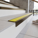 Solid brass stair nosing 59mm raked back slimline in antique bronze finish with yellow castellated anti-slip insert, fitted to a stair tread