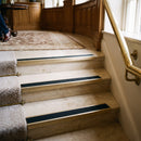 Solid brass stair nosings with black castellated anti-slip inserts fitted to a hotel staircase, polished brass finish