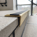 Close-up of the insert channel, small-radius nose and raked-back riser leg on the solid brass stair nosing, satin brass finish