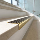 Solid brass stair nosing 59mm raked back slimline in polished brass finish with antique bronze anti-slip insert, fitted to a stair tread