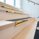 Solid brass stair nosing 59mm raked back slimline in polished brass finish with black olympic grip anti-slip insert, fitted to a stair tread