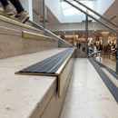 Solid brass stair nosing 59mm raked back slimline in polished brass finish with black castellated anti-slip insert, fitted to a stair tread