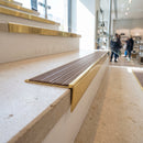 Solid brass stair nosing 59mm raked back slimline in polished brass finish with fawn castellated anti-slip insert, fitted to a stair tread