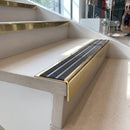 Solid brass stair nosing 59mm raked back slimline in polished brass finish with granite castellated anti-slip insert, fitted to a stair tread
