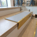Solid brass stair nosing 59mm raked back slimline in polished brass finish with light grey smooth textured anti-slip insert, fitted to a stair tread