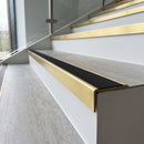 Solid brass stair nosing 59mm raked back slimline in satin brass finish with black smooth textured anti-slip insert, fitted to a stair tread