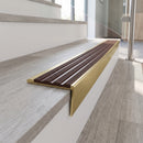 Solid brass stair nosing 59mm raked back slimline in satin brass finish with claret castellated anti-slip insert, fitted to a stair tread