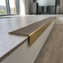 Solid brass stair nosing 59mm raked back slimline in satin brass finish with fawn castellated anti-slip insert, fitted to a stair tread