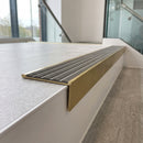 Solid brass stair nosing 59mm raked back slimline in satin brass finish with flint castellated anti-slip insert, fitted to a stair tread