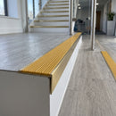 Solid brass stair nosing 59mm raked back slimline in satin brass finish with gold castellated anti-slip insert, fitted to a stair tread