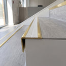 Solid brass stair nosing 59mm raked back slimline in satin brass finish with white castellated anti-slip insert, fitted to a stair tread