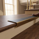 Solid brass stair nosing, 59.5mm tread with a 30mm raked-back front, in Antique Brass finish with Black Smooth Textured insert, fitted to a staircase
