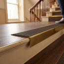 Solid brass stair nosing, 59.5mm tread with a 30mm raked-back front, in Antique Brass finish with Granite Castellated insert, fitted to a staircase