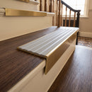 Solid brass stair nosing, 59.5mm tread with a 30mm raked-back front, in Antique Brass finish with Light Grey Castellated insert, fitted to a staircase