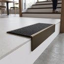 Solid brass stair nosing, 59.5mm tread with a 30mm raked-back front, in Antique Bronze finish with Black Olympic Grip insert, fitted to a staircase