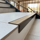 Solid brass stair nosing, 59.5mm tread with a 30mm raked-back front, in Antique Bronze finish with Ivory Castellated insert, fitted to a staircase