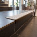 Solid brass stair nosing, 59.5mm tread with a 30mm raked-back front, in Antique Bronze finish with Polar Grey Castellated insert, fitted to a staircase