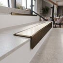 Solid brass stair nosing, 59.5mm tread with a 30mm raked-back front, in Antique Bronze finish with Porth Stone Smooth Textured insert, fitted to a staircase