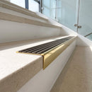 Solid brass stair nosing, 59.5mm tread with a 30mm raked-back front, in Polished Brass finish with Antique Bronze insert, fitted to a staircase