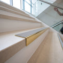 Solid brass stair nosing, 59.5mm tread with a 30mm raked-back front, in Polished Brass finish with Light Grey Castellated insert, fitted to a staircase
