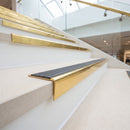 Solid brass stair nosing, 59.5mm tread with a 30mm raked-back front, in Polished Brass finish with Peat Castellated insert, fitted to a staircase