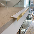 Solid brass stair nosing, 59.5mm tread with a 30mm raked-back front, in Polished Brass finish with Polar Grey Castellated insert, fitted to a staircase
