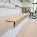 Solid brass stair nosing, 59.5mm tread with a 30mm raked-back front, in Polished Brass finish with Porth Stone Smooth Textured insert, fitted to a staircase