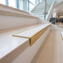 Solid brass stair nosing, 59.5mm tread with a 30mm raked-back front, in Polished Brass finish with White Castellated insert, fitted to a staircase