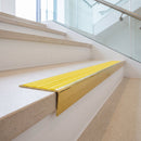 Solid brass stair nosing, 59.5mm tread with a 30mm raked-back front, in Polished Brass finish with Yellow Castellated insert, fitted to a staircase