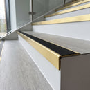 Solid brass stair nosing, 59.5mm tread with a 30mm raked-back front, in Satin Brass finish with Black Smooth Textured insert, fitted to a staircase