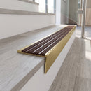 Solid brass stair nosing, 59.5mm tread with a 30mm raked-back front, in Satin Brass finish with Claret Castellated insert, fitted to a staircase
