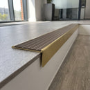 Solid brass stair nosing, 59.5mm tread with a 30mm raked-back front, in Satin Brass finish with Fawn Castellated insert, fitted to a staircase