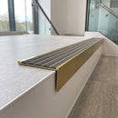 Solid brass stair nosing, 59.5mm tread with a 30mm raked-back front, in Satin Brass finish with Flint Castellated insert, fitted to a staircase