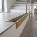 Solid brass stair nosing, 59.5mm tread with a 30mm raked-back front, in Satin Brass finish with Granite Castellated insert, fitted to a staircase