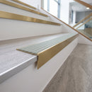 Solid brass stair nosing, 59.5mm tread with a 30mm raked-back front, in Satin Brass finish with Jade Castellated insert, fitted to a staircase