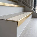 Solid brass stair nosing, 59.5mm tread with a 30mm raked-back front, in Satin Brass finish with Porth Stone Smooth Textured insert, fitted to a staircase