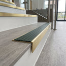 Solid brass stair nosing, 59.5mm tread with a 30mm raked-back front, in Satin Brass finish with Spruce Castellated insert, fitted to a staircase