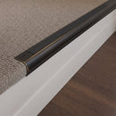 Antique Bronze finish - 63.5mm solid brass bullnose stair nosing fitted to a carpeted step, dark aged bronze with a black anti-slip insert