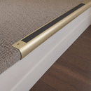 Satin Brass finish - 63.5mm solid brass bullnose stair nosing fitted to a carpeted step, brushed pale gold with a black anti-slip insert