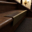 Solid brass stair nosing 71mm raked back in antique brass with antique bronze insert fitted on a dark oak hotel stairwell