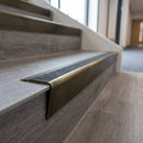 Solid brass stair nosing 71mm raked back in antique brass with black olympic grip insert fitted on a vinyl plank school staircase