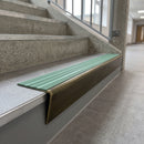 Solid brass stair nosing 71mm raked back in antique brass with jade castellated insert fitted on a vinyl plank school staircase