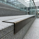 Solid brass stair nosing 71mm raked back in antique brass with light grey castellated insert fitted on a granite atrium staircase