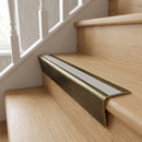 Solid brass stair nosing 71mm raked back in antique brass with light grey smooth textured insert fitted on an oak domestic hallway staircase