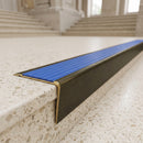 Solid brass stair nosing 71mm raked back in antique brass with mid blue castellated insert fitted on a terrazzo museum foyer staircase