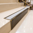 Solid brass stair nosing 71mm raked back in antique brass with polar grey castellated insert fitted on a porcelain tiled hotel lobby staircase