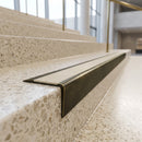 Solid brass stair nosing 71mm raked back in antique brass with porth stone castellated insert fitted on a terrazzo museum foyer staircase