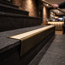 Solid brass stair nosing 71mm raked back in antique brass with porth stone smooth textured insert fitted on a slate restaurant staircase