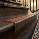 Solid brass stair nosing 71mm raked back in antique brass with rustic castellated insert fitted on a dark oak hotel stairwell