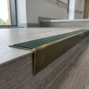 Solid brass stair nosing 71mm raked back in antique brass with spruce castellated insert fitted on a vinyl plank school staircase